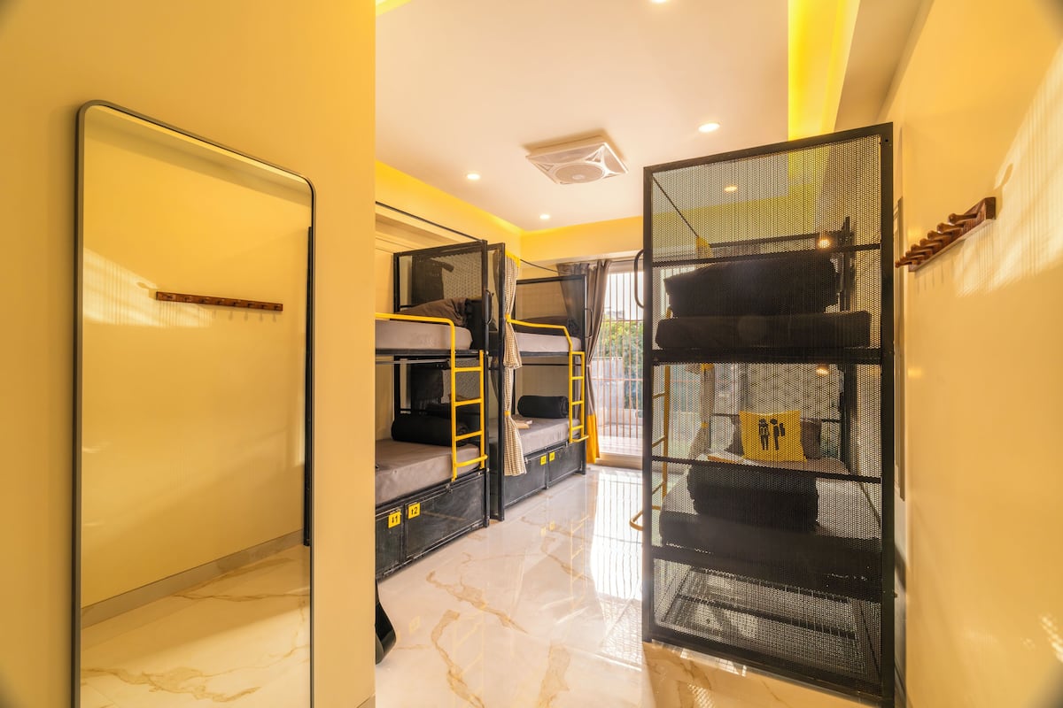 A hotel room with bunk beds, a large mirror, and a sliding door leading to a balcony.