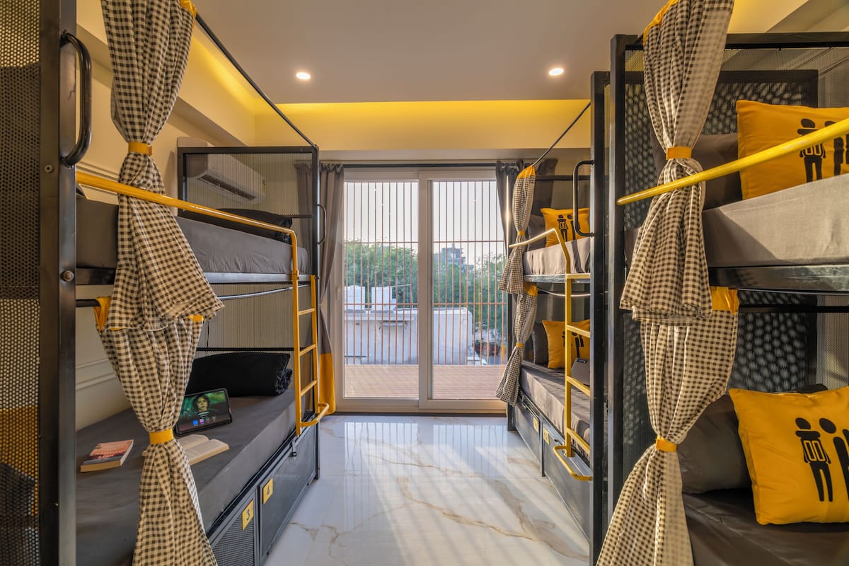 A compact hotel room with bunk beds, a small desk, and a sliding glass door leading to an outdoor area.