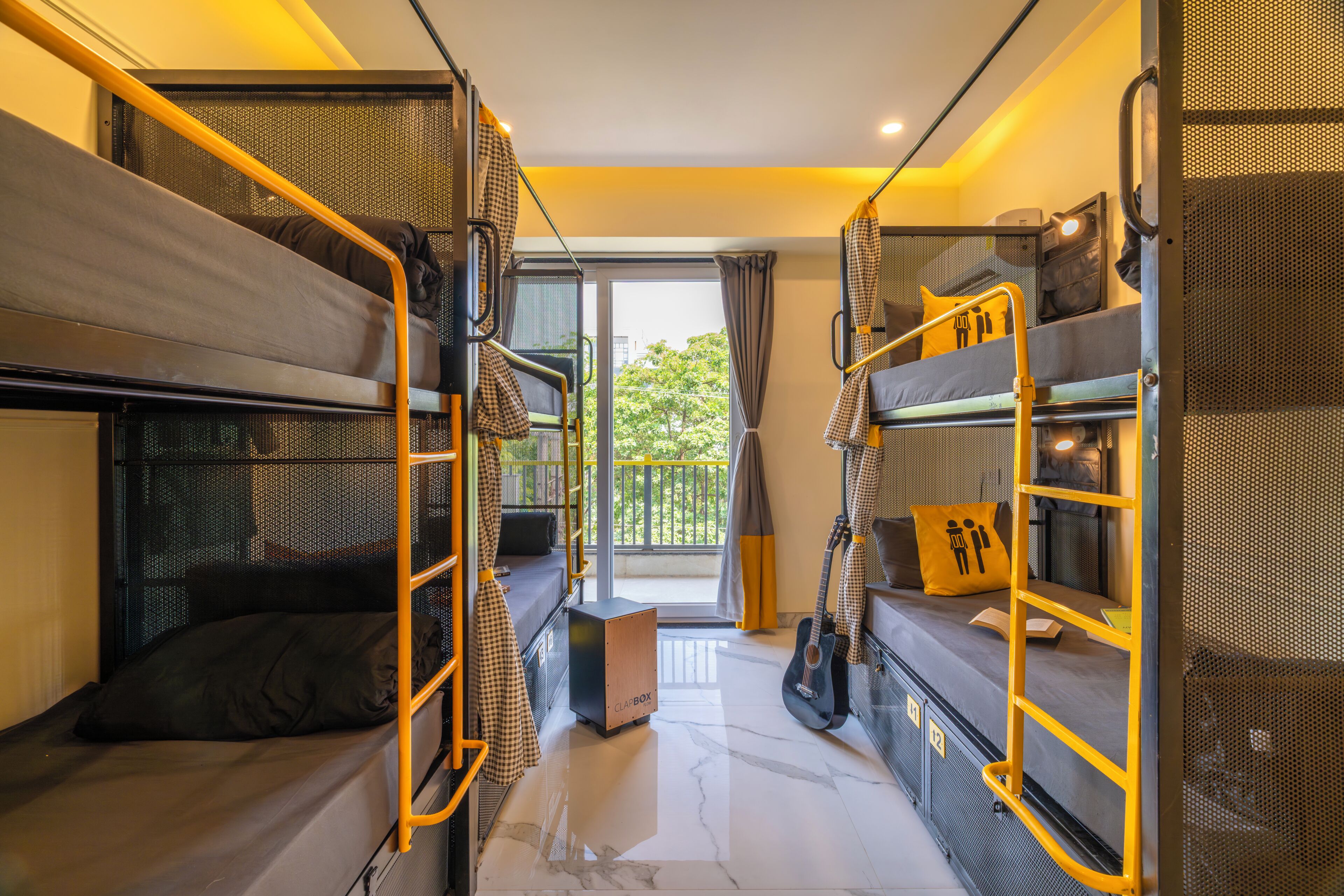 Habitación compacta con literas, una mesita pequeña, una guitarra y vistas a través de un ventanal.