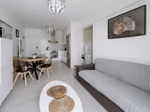 Ein modernes Wohnzimmer mit einer Couch, einem Essbereich mit Stühlen und einer Küche im Hintergrund.
