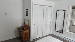 Ein Schlafzimmer mit weißer Tür, einem hölzernen Schminktisch, einem Spiegel und einem Bett.
