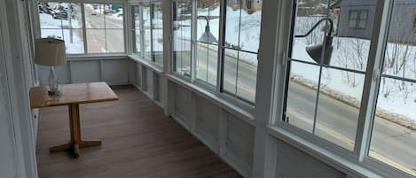 Un pasillo estrecho y cerrado con ventanas amplias, un banco de madera y una mesa con lámpara.