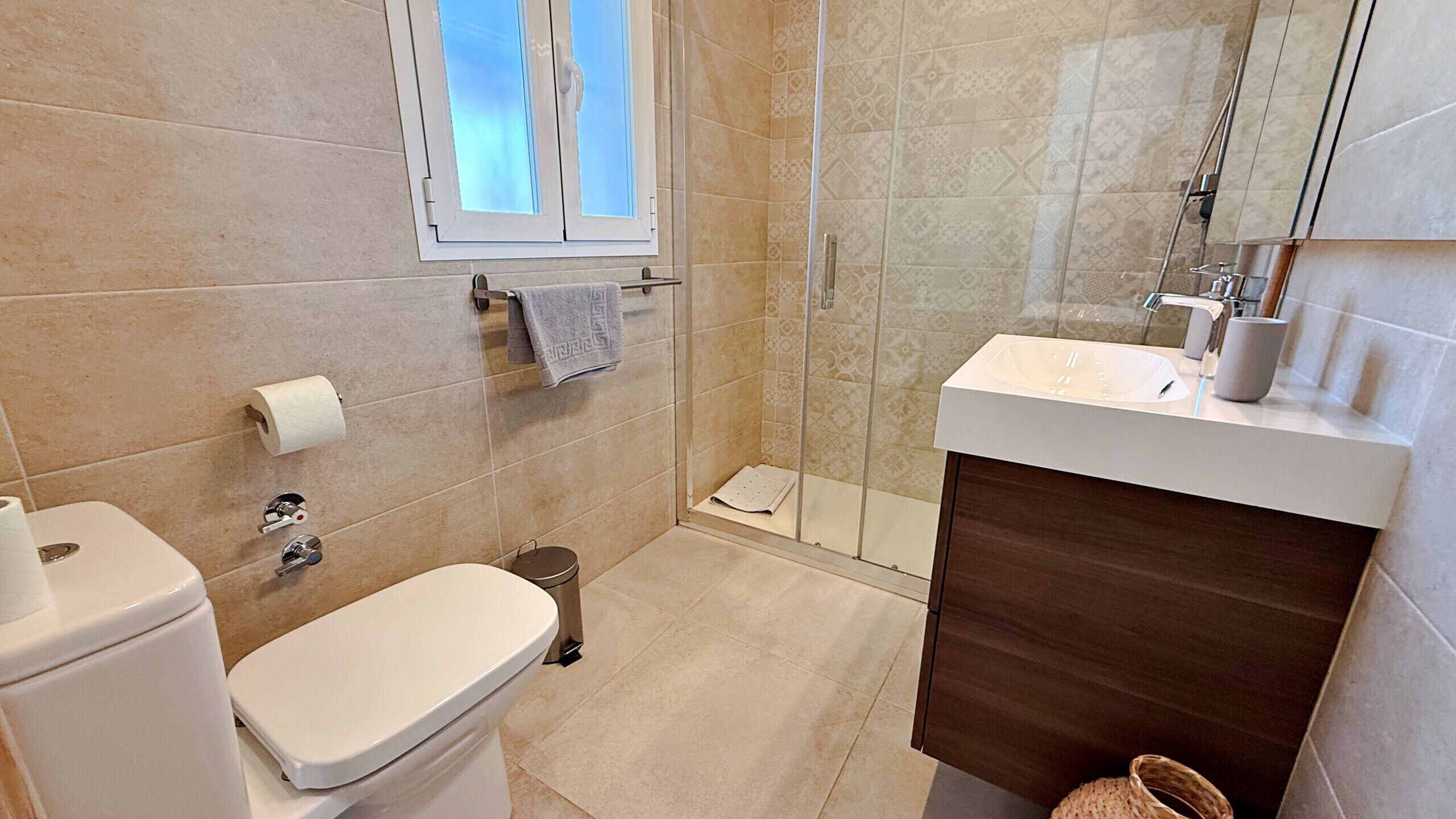 A bathroom with a toilet, a shower, a sink, and a window.