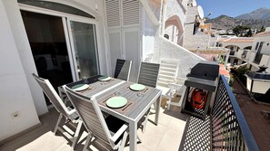 A balcony with a table set for two, outdoor furniture, and a grill. - AP426 VERANO AZUL SUNSHINE (Nerja)