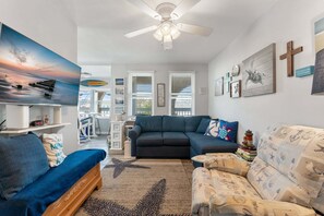 A living room with a sofa, a coffee table, a TV, and a ceiling fan.