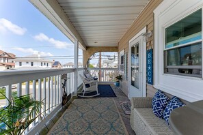 A covered porch with a rocking chair, a sofa with patterned cushions, and a potted plant. - 5600 Seaview Ave, Unit 34 (Wildwood Crest)