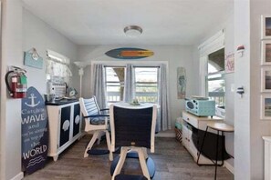 Une cuisine compacte avec un coin repas, une décoration sur le thème du surf et une petite table.