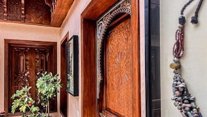 A wooden door with intricate carvings, a potted plant, and a wall-mounted decorative item. - Riad jamaique (Marrakech)