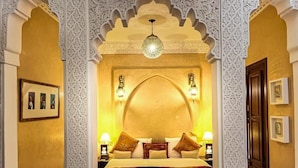 A room with a bed, ornate white wall patterns, and a chandelier. - Riad jamaique (Marrakech)