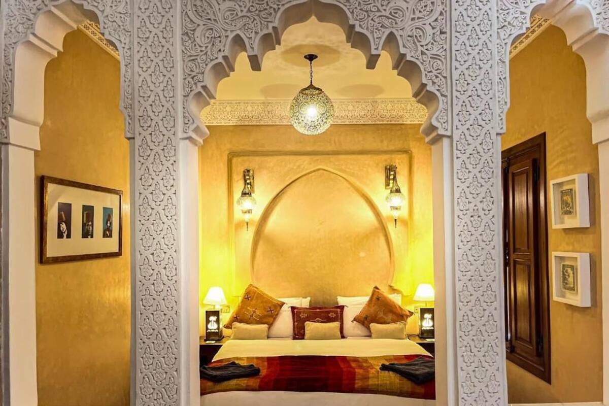 Une chambre avec un lit, des motifs décoratifs blancs sur les murs et un lustre.