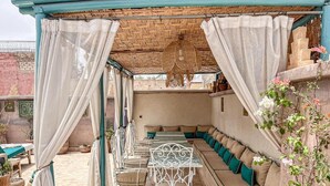 An outdoor patio with a table and chairs, a sofa, and a hanging light fixture. - Riad jamaique (Marrakech)