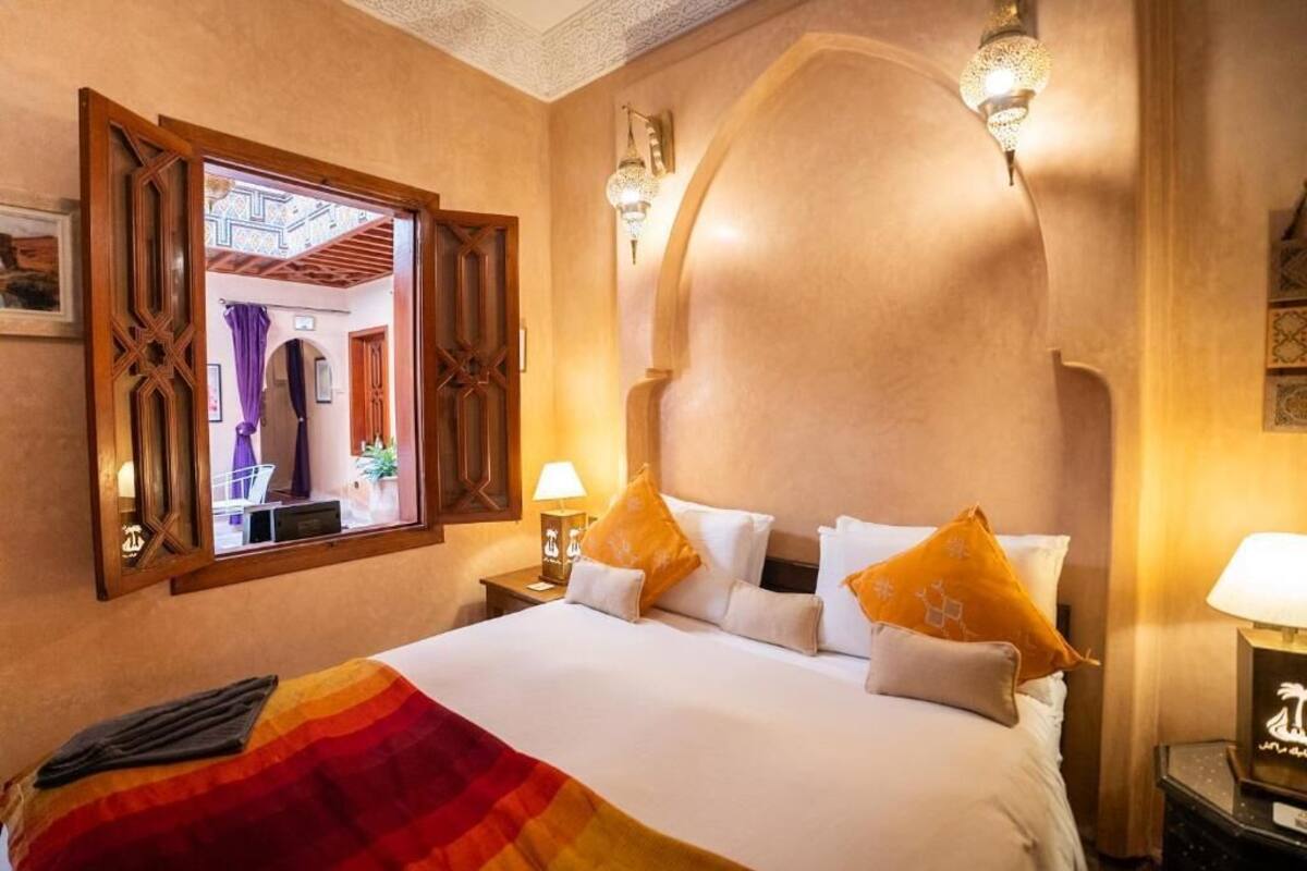 Une chambre d’hôtel avec un lit, une table de chevet, une lampe et un miroir.
