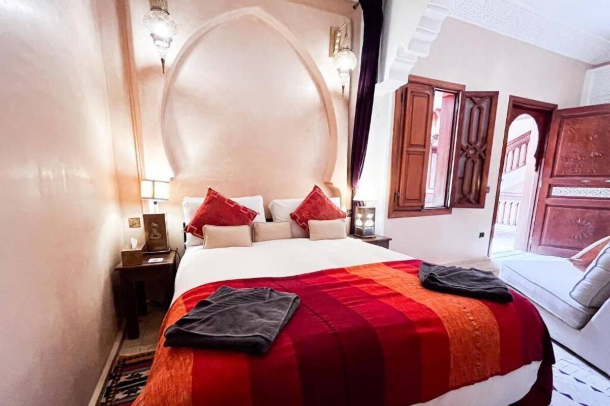 Une chambre d’hôtel avec un grand lit, une table de chevet, une lampe et une vue sur l’extérieur.