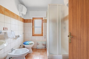 Ein Badezimmer mit Toilette, Bidet, Waschbecken und Duschbereich.