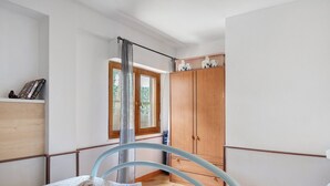 A hotel room with a bed, a wooden wardrobe, a window, and a curtain. - Apartment 'Zakaria' with Mountain View, Wi-Fi and Air Conditioning (Foxi Lioni)