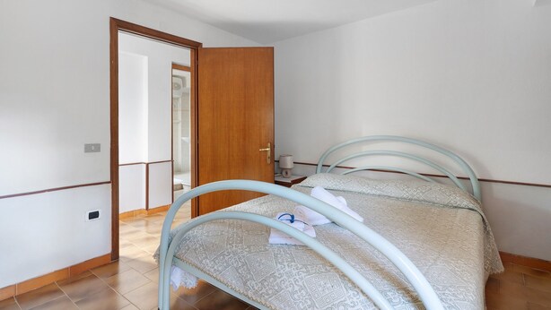 A small, clean room with a single bed, a wooden door, and a tiled floor. - Apartment 'Zakaria' with Mountain View, Wi-Fi and Air Conditioning (Foxi Lioni)