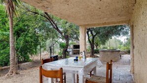 An outdoor patio with a table and chairs, surrounded by trees and a concrete structure. - Apartment 'Zakaria' with Mountain View, Wi-Fi and Air Conditioning (Foxi Lioni)