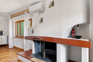 Ein Zimmer mit Kamin, Fenster und einer kleinen Ablage mit Flasche und Schale.