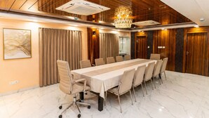 A conference room with a long table, chairs, a chandelier, and wooden paneling. - The Universe (Kolkata)