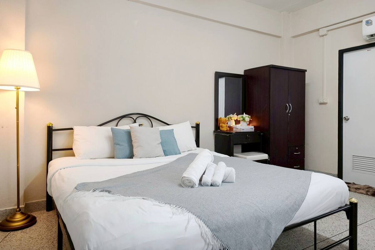 Habitación de hotel con cama, lámpara de noche, cómoda y armario.
