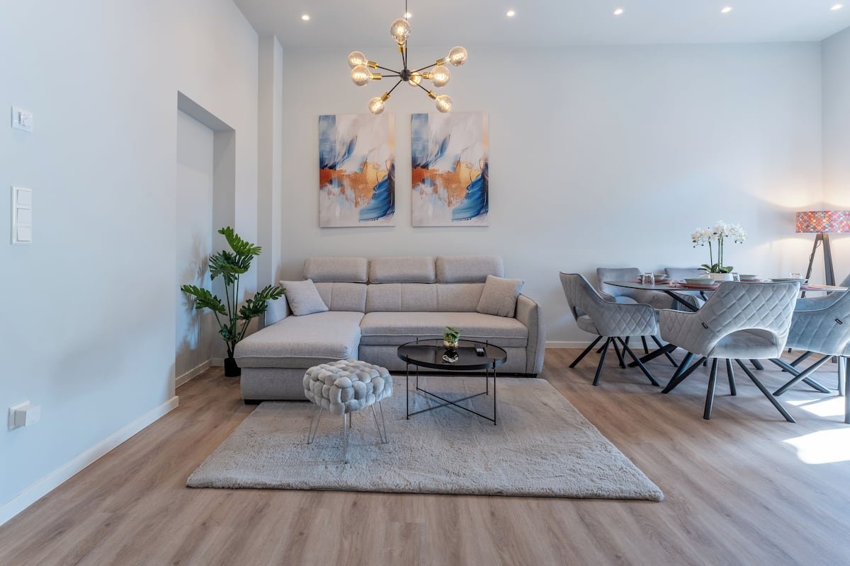 A modern living room with a sectional sofa, a round coffee table, and a dining area with chairs.