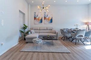 Una sala de estar moderna con un sofá modular, una mesa de centro redonda y un comedor con sillas.