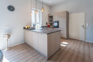 Una cocina moderna con una isla central, luces colgantes y un reloj en la pared.