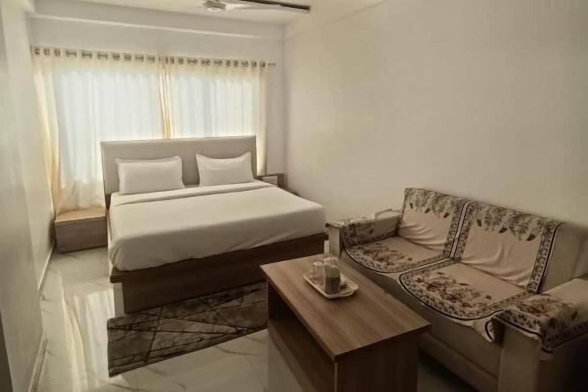 A bedroom with a bed, a sofa, a coffee table, and a ceiling fan.
