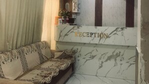 A reception area with a marble reception desk, a sofa, curtains, and a wall-mounted air conditioner.