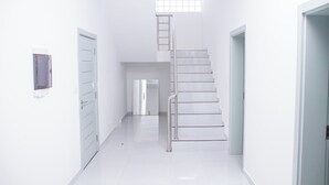 A bright, modern hallway with a staircase, white walls, and a small window. - Hotel Kilimanjaro (Luanda)