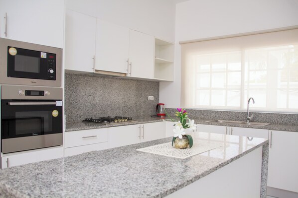 A modern kitchen with built-in appliances, granite countertops, and a window providing natural light.