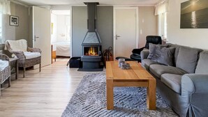 Ein gemütliches Wohnzimmer mit Kamin, Sofa, Sessel und Couchtisch.