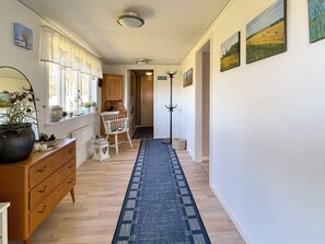 A hallway with a wooden dresser, a chair, a coat rack, and a rug. - 4 Person Holiday Home in Borgholm (Borgholm)