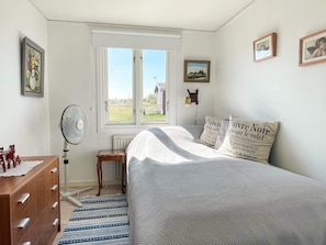 A bedroom with a bed, a window, a radiator, a wooden dresser, and a fan. - 4 Person Holiday Home in Borgholm (Borgholm)