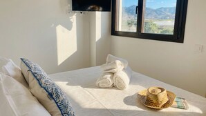 A bedroom with a bed, a TV mounted on the wall, and a window with a view of the landscape. - Apartamento Sea Blue D D by At Home Costa del Sol (Torrox)