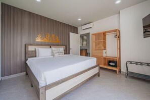 Une chambre à coucher comprenant un lit, une tête de lit en bois, une armoire, un banc et un climatiseur fixé au mur.