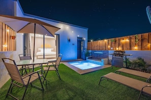Une terrasse extérieure avec une piscine, des sièges et un espace barbecue.