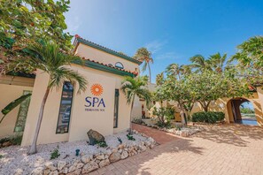 Ein Spa namens 'SPA TIERRA DEL SOL' mit einem gefliesen Dach, Palmen und einem gepflasterten Eingang.