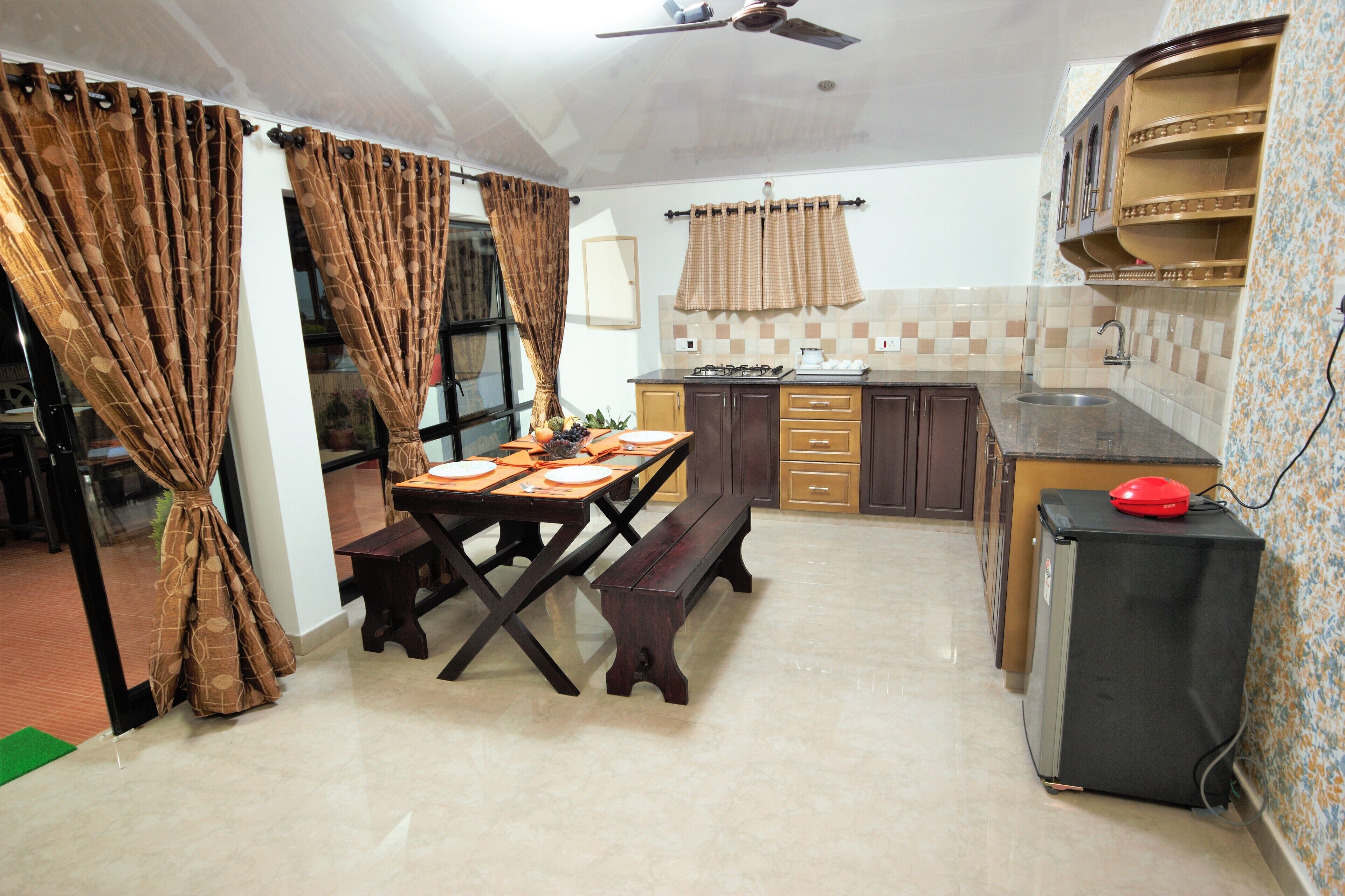 Una cocina con una mesa de comedor, banco, refrigerador y estantes empotrados.