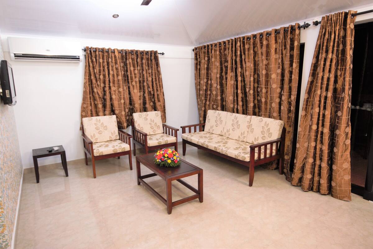 Una sala de estar con un sofá, dos sillones, una mesa de centro y un televisor.
