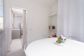 A modern, minimalist room with a white table, a small potted plant, and a bookshelf. - Chiaia 74 Rooftop By Dimorra (Naples)