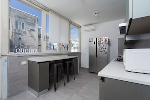 A modern kitchen with a large window, a refrigerator, and a microwave. - Chiaia 74 Rooftop By Dimorra (Naples)