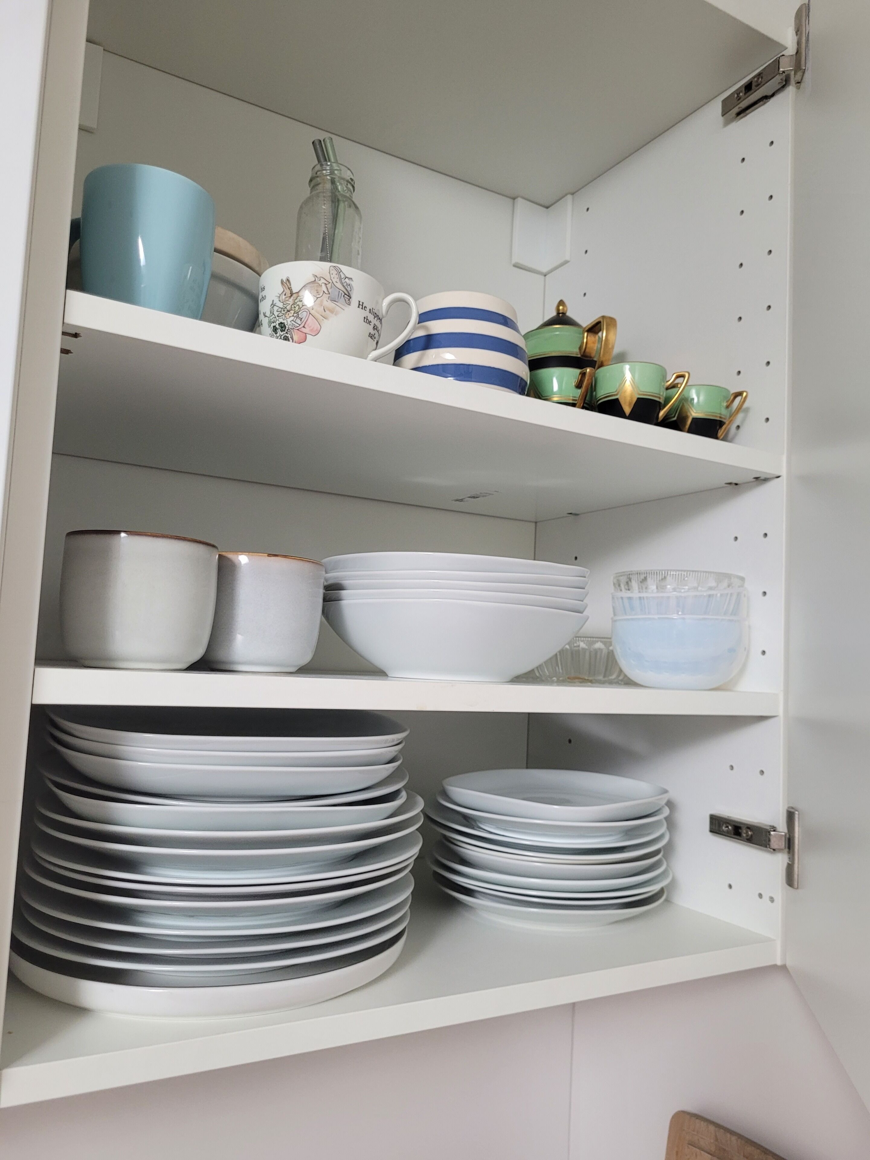 Een keukenkast met planken vol servies en kookgerei.