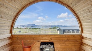 Une cabane en bois avec une grande fenêtre en arc de cercle, un banc en bois et un seau.