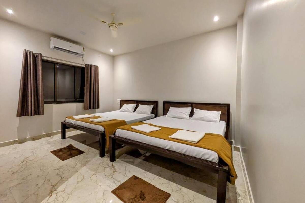 A room with two beds, an air conditioning unit, a ceiling fan, and a window with curtains.