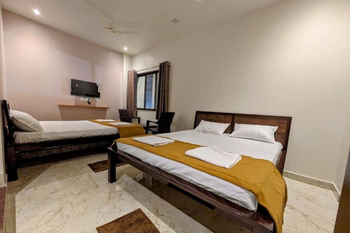 A hotel room with two beds, a TV, a desk, and a window.
