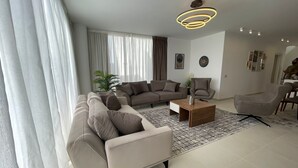 Una sala de estar moderna con un sofá modular, una mesa de centro y una zona de comedor con sillas.