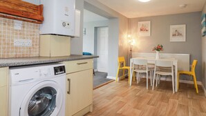 Una cocina compacta con lavadora, un comedor con mesa y sillas, y un radiador.