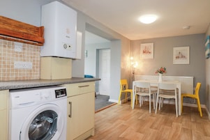 Una cocina compacta con lavadora, un comedor con mesa y sillas, y un radiador.