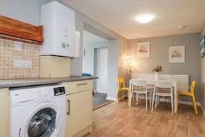 Una cocina compacta con lavadora, un comedor con mesa y sillas, y un radiador.
